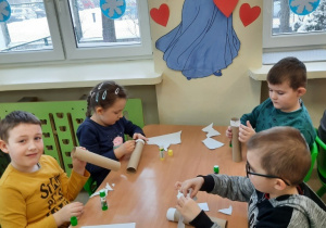 Dzieci wykonują wesołe bałwanki z wykorzystaniem rolek po papierze