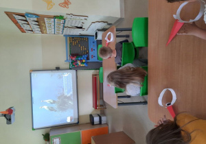 Dzieci oglądają prezentację multimedialną na temat życia bocianów