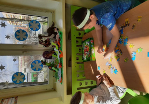 Przedszkolaki układają puzzle z dinozaurami