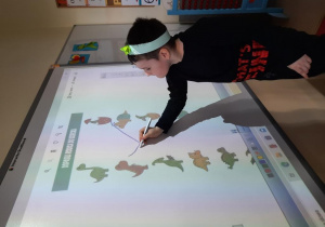 Dzieci rozwiązują zadania na tablicy multimedialnej