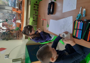 Dzieci wykonują orła z rolki po papierze
