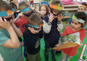 Dzieci oglądają ilustracje dinozaurów w okularach trójwymiarowych