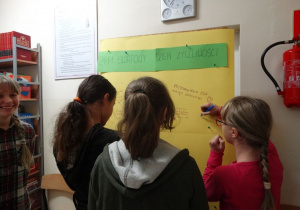 Uczniowie piszą pozdrowienia na tablicy