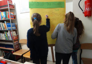 Uczniowie piszą pozdrowienia na tablicy