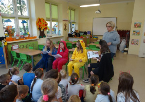 Uczennice podczas czytania książki w oddziale przedszkolnym z nauczycielką