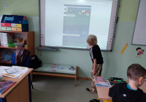 Chłopiec czytający zadanie na tablicy multimedialnej.