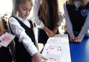 uczennica pierwszej klasy umieszcza odcisk kciuka w kronice szkolnej