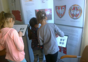 uczniowie oglądają znaki Państwa Polskiego